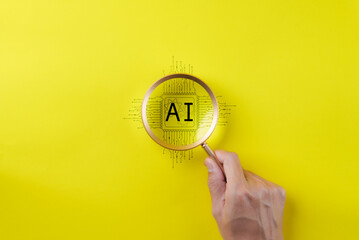AI Artificial Intelligence technology concept. Man hand holding a magnifying glass focusing on an AI chip on yellow background. AI prompt generator, Machine learning, Marketing with robot, copy space, - obrazy, fototapety, plakaty