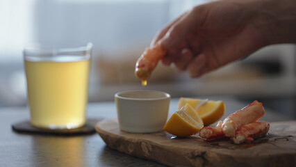 Man dip crab leg into pesto sauce with ginger beer on background