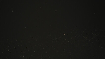 Dust particles float in sunlight on black background