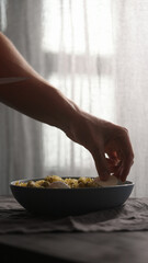 add mozzarella to pesto fusilli in blue bowl with natural light