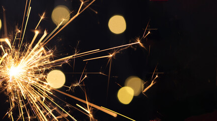Burning sparkler with golden bokeh light background. New year party background. New year sparkles.