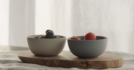 strawberries and blueberries in bowls on wood table