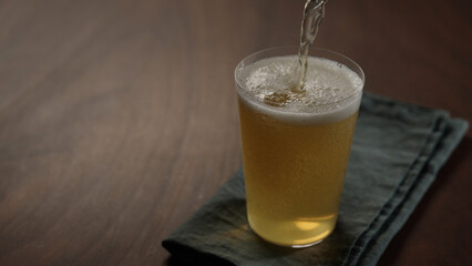 pour apple cider into tumbler glass on wood table with copy space