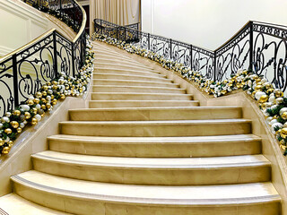 Marble staircase with beautiful black wrought iron railings and Christmas decorations frontal view
