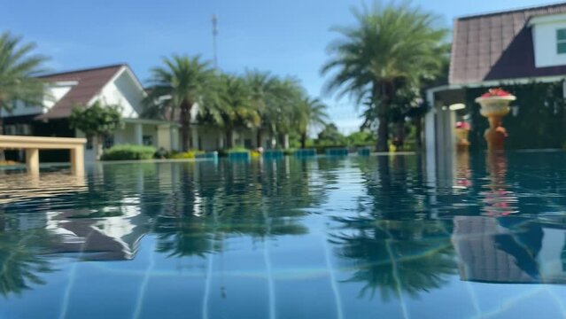 Water surface swimming pool close up view with blurred residential homes and palm tree outdoor summer time blue sky