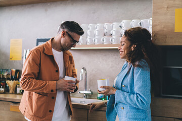 Smiling diverse couple with coffee in kitchen