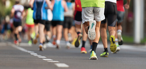 Marathon runners running on city road, large group of runners, close-up legs runners running sport...