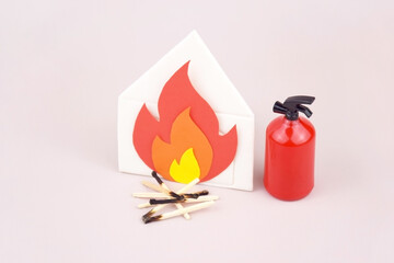 A box of matches placed next to a toy red fire extinguisher against a light background.
