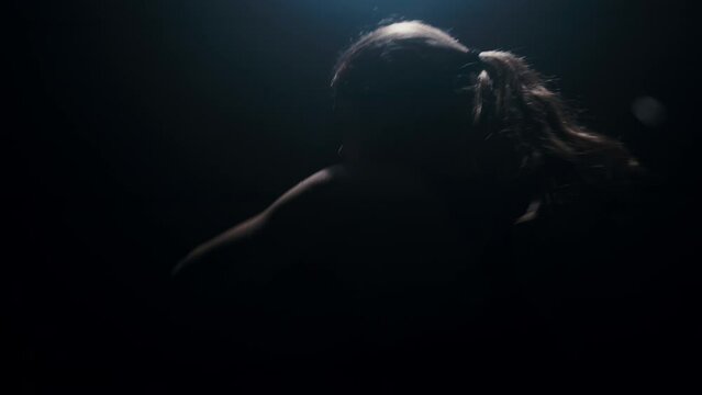 Woman boxer in dark room practicing shadow boxing, female fighter practicing fast punches with back light in slow motion, 4k