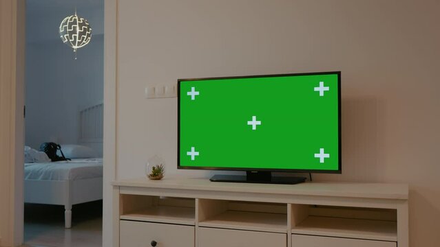 Pregnant female walking around and TV with green screen in living room. Green screen chroma key television in the living room and future mom putting things away.
