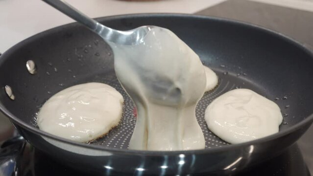 frying small thick pancakes Oladyi in a frying pan, Russian cuisine