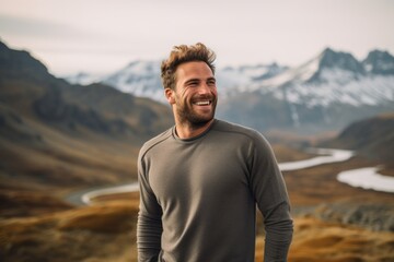 Portrait of a happy man in his 30s showing off a thermal merino wool top against a backdrop of mountain peaks. AI Generation