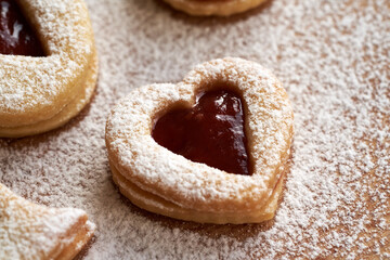 Fototapeta na wymiar Heart shaped homemade Linzer Christmas cookie filled with red strawberry marmalade and dusted with sugar, closeup