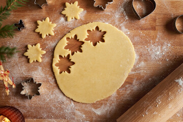 Cutting out star shapes from rolled out dough to prepare homemade Linzer Christmas cookies