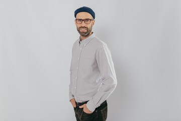Profile shot of attractive unshaven man dressed formally, wears optical glasses, models over white...