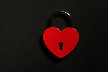 Metallic red heart shaped lock on a black background with copy space