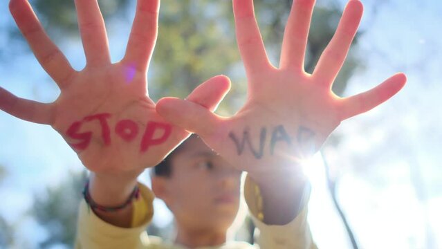 Child's hands with 'Stop War' written, promoting anti-war, pacifism, and peace. Advocating against weapon sales, violence, and protecting children from war's impact. Supports Peace Day and opposes arm