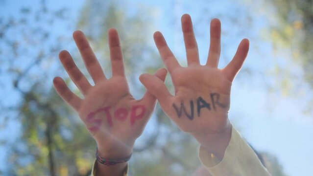Child's hands with 'Stop War' written, promoting anti-war, pacifism, and peace. Advocating against weapon sales, violence, and protecting children from war's impact. Supports Peace Day and opposes arm