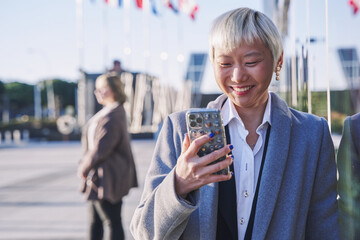 asian woman in formal wear using her smart phone. young woman with short white hair.
