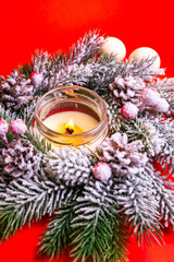 Beautiful christmas tree wreath with artificial snow and pine cones, white candle and white christmas toys from above on red background.