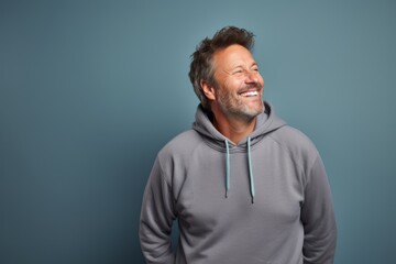 Fototapeta premium Portrait of a joyful man in his 50s wearing a zip-up fleece hoodie against a pastel gray background. AI Generation