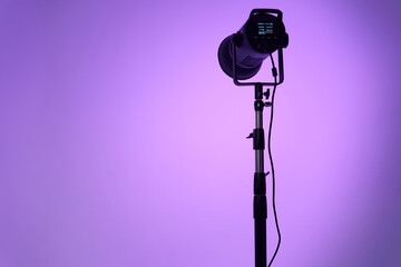 Studio flash on a tripod against a background of colored light. Pulsed light for professional use...