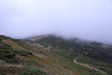 Morning view from the Dragobrat mountain peaks in Carpathian mountains, Ukraine. Cloudy and foggy landscape around Drahobrat Peaks in early morning