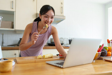 Confident young woman in exercise clothes eating banana and talking Live broadcast via mobile...