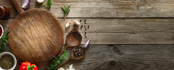 Cooking background. Old cutting board with spices and ingredients for preparation food on a wooden table top view