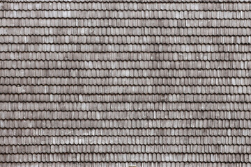 Gray wooden roof tiles background texture. A close up of old gray roof covered with wooden tiles or shingles
