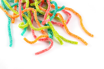 Multicolored jelly candies in the shape of the sticks sprinkled with sugar on a white background