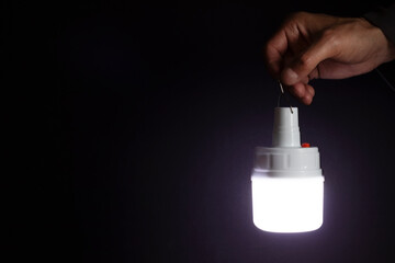 A man's hand holds a portable rechargeable LED emergency light