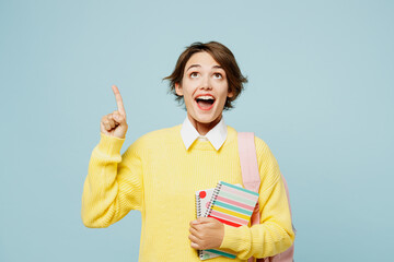 Young woman student wears casual clothes yellow sweater backpack bag hold books holding index...