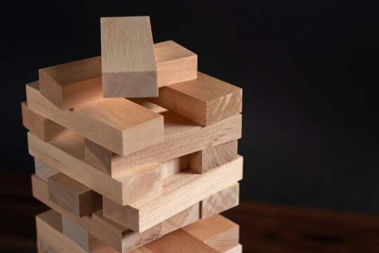 Jenga tower made of wooden blocks on dark background, space for text