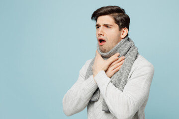 Side view young ill sick man in gray sweater scarf hold neck suffer from sore throat isolated on...