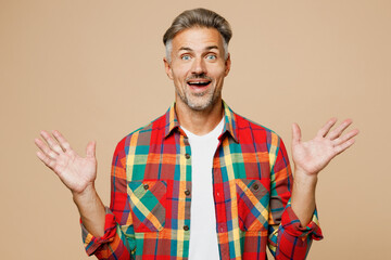Adult surprised shocked excited man he wears red shirt white t-shirt casual clothes look camera spread hands isolated on plain pastel light beige color background studio portrait. Lifestyle concept.