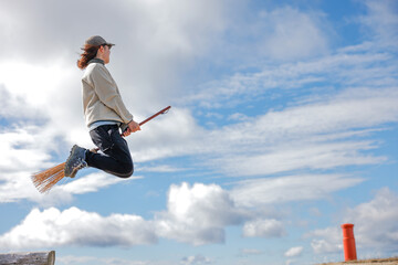 箒で空飛ぶ女性