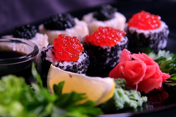  Three types of sushi rolls with white and black sesame seeds with black paddlefish caviar, red chum salmon caviar and pink salmon on one plate. Delicious food, beautiful presentation.