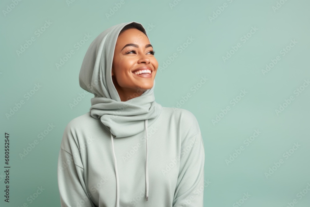 Wall mural portrait of a cheerful woman in her 30s sporting a comfortable hoodie against a pastel or soft color - Wall murals