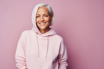 Fototapeta premium Portrait of a happy woman in her 40s sporting a comfortable hoodie against a pastel or soft colors background. AI Generation