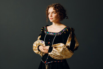 Portrait of a young aristocratic woman dressed in a medieval dress on dark background