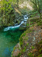 Fototapeta premium Drone panorama above a rapid mountain river forming stepped cascades and ponds when flowing through eroded large stone pieces. Latorita Mountains, Carpathia, Romania.