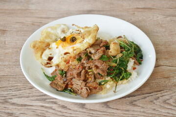 spicy stir fried slice beef meat with basil leaf and chili on rice topping egg in plate