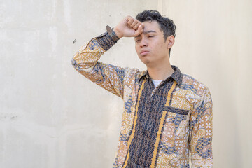 Young Indonesian wear batik traditional culture Indonesia with cough gesture. The photo is suitable...
