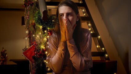 Portrait of scared and terrified woman closing her mouth while sitting on stairs on Christmas or...