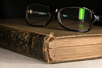Reading glasses on a thick old book with a leather cover