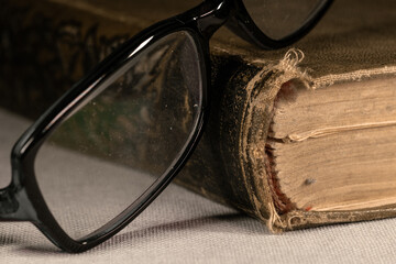Reading glasses on a thick old book with a leather cover