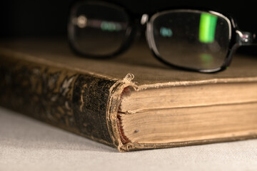 Reading glasses on a thick old book with a leather cover
