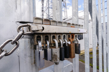 Multiple locks on a security gate. The removal of any one lock allows the gate to be opened.