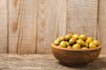Green olives on a white wooden background. Various types of olives in bowls and olive oil with fresh olive leaves. Copy space. Place for text. Mediterranean food. Vegan.